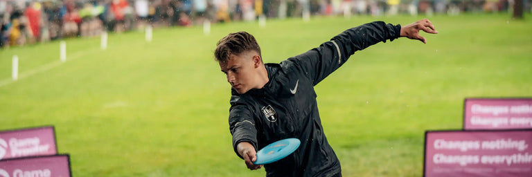 Disc golfer der er igang med at kaste sin driver imens en masse mennesker i baggrunden der kigger på