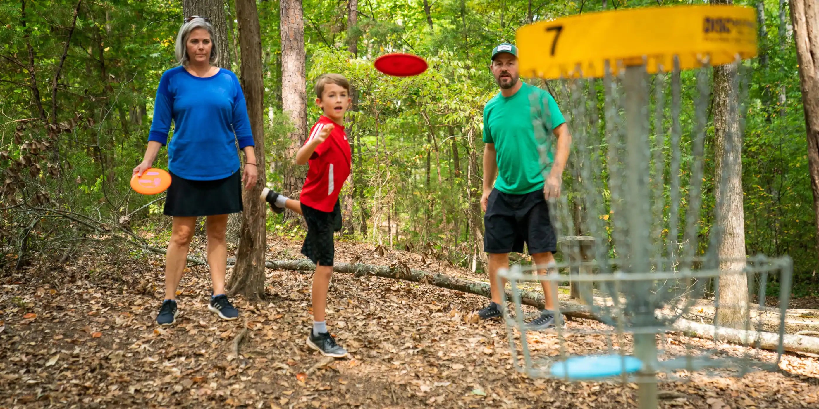 Et barn spiller disc golf med sine forældre